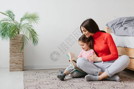 快乐的家庭母子女儿躺在床上看书图片