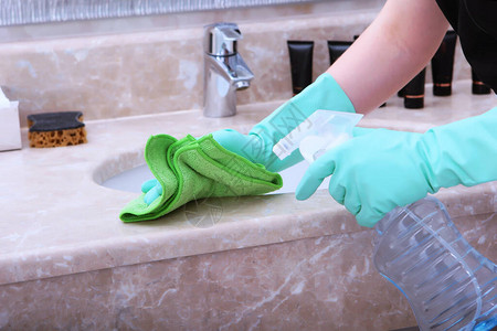 戴着绿色橡胶手套的女手清洁浴室大理石台面的边缘一张认不出来的照片酒店清洁和卫生的概念顶视图片