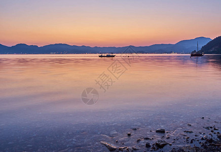 天上人间海边的海边晚上山上和小船在海中天空下黄背景