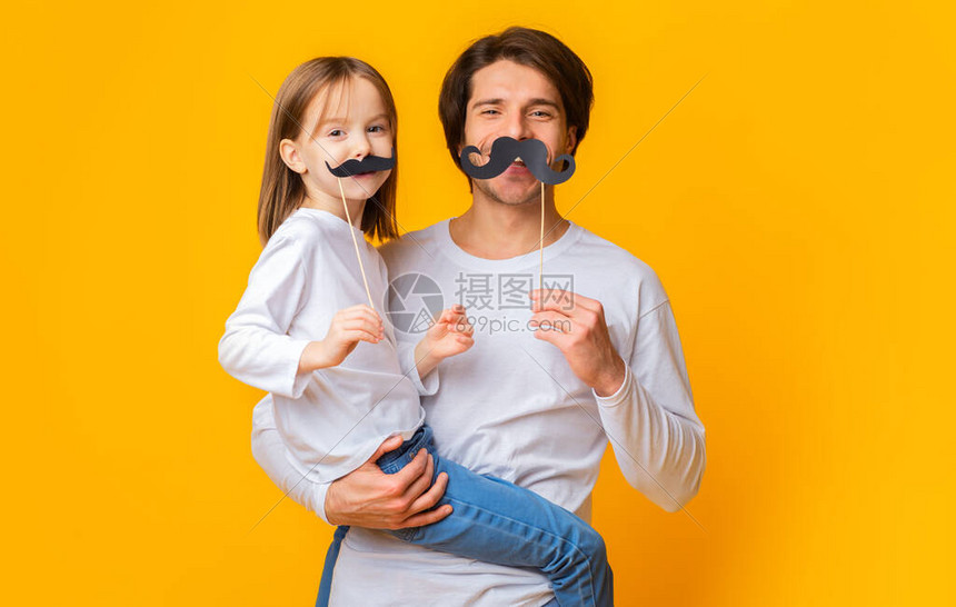快乐的父女在黄色工作室背景下玩乐的肖像图片
