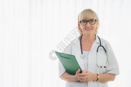 拥有剪贴板的高级女医生在病人床边站立图片