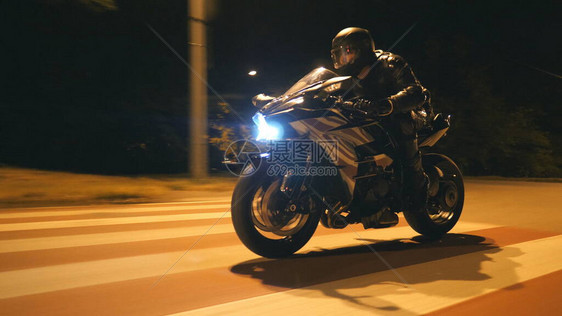 戴着头盔的年轻人在晚上的城市街道上骑着现代黑色摩托车快速骑行摩托车手在夜间空荡的路上赛车他的摩托车驾驶自行车的人自由和爱好图片