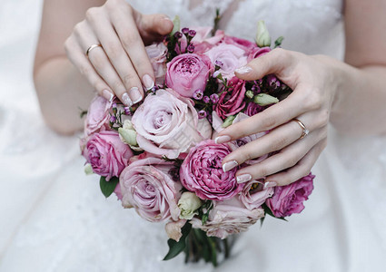 有戒指的新娘的手拿着婚礼花束婚礼装饰品特写图片