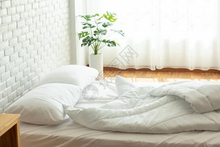 早上卧室用白枕头和带自然光的毯子醒来后Messy床Messy床和Coz背景图片