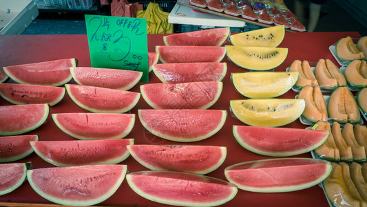 新加坡市场摊位上鲜切的红色黄色西瓜和哈密瓜包裹在保鲜膜中图片