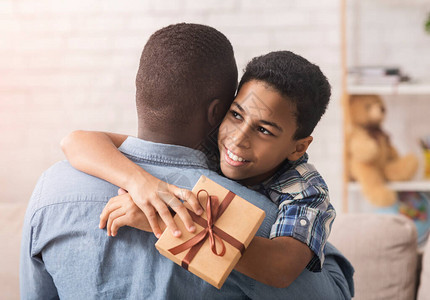 快乐的父亲日快乐的黑男孩抱着爸送他礼物盒回家图片