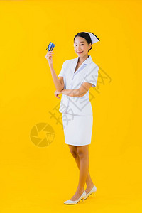有着黄色孤立背景的信用卡的亚洲年轻女泰籍护士Thai图片