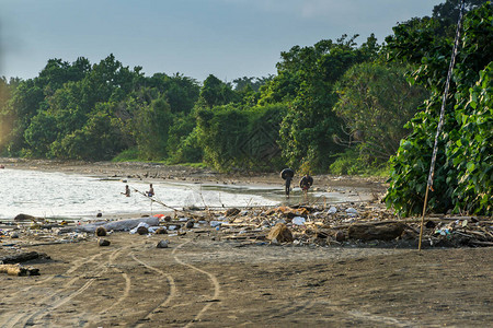 巴厘岛海滩与渔民与海滩上的黑色橡胶圈有一堆废物通过图片