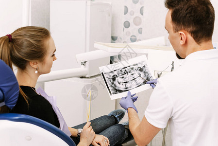牙医给一个可爱的女孩看病人牙齿的X光片图片