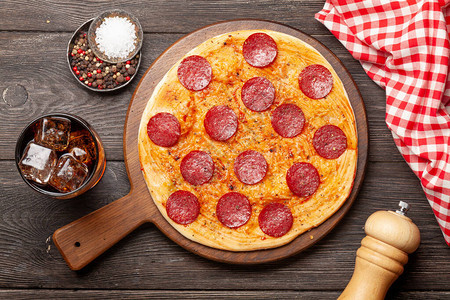 美味的自制披萨加辣椒尼香肠和冰的可乐图片