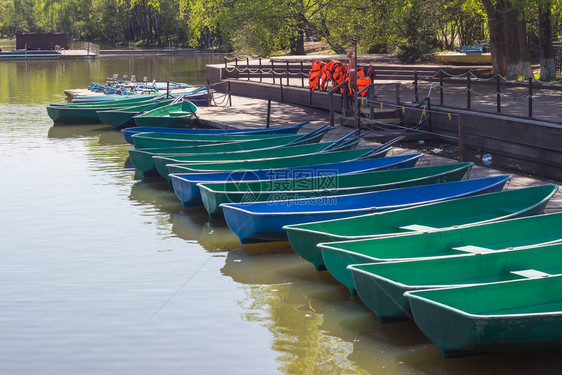 大型城市池塘码头上的绿色和蓝色游艇图片