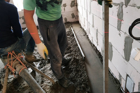 雇员从事沙水泥地板的铺垫砂水泥地板的盖子供取暖图片