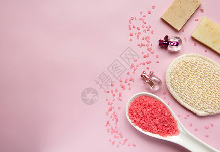 白色勺子里的天然浴盐浴海绵手工皂粉红色背景的香水瓶身体护理有机沐浴产品的概念温泉化妆品平背景图片