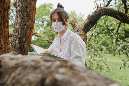 穿着白衬衫和蓝色牛仔裤的年轻女孩坐在大自然上图片