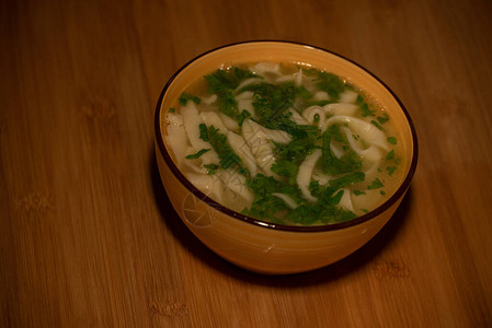 鸡肉面条汤橙色盘子里的橙色桌布上的鸡肉和面条汤美食摄影热菜肉汤配面条鸡肉背景图片