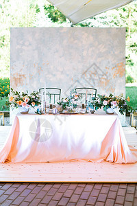新婚夫妇新郎娘中央餐桌的整体布局在露天帐篷婚礼上关于自然背景的欢迎晚宴柔和的设计插花和烛图片