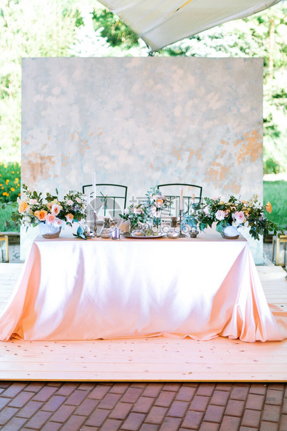 新婚夫妇新郎娘中央餐桌的整体布局在露天帐篷婚礼上关于自然背景的欢迎晚宴柔和的设计插花和烛图片