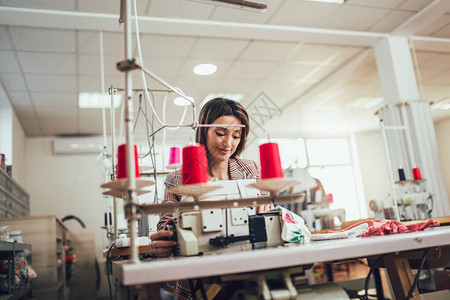 纺织业青年工人在生产线上缝纫背景图片