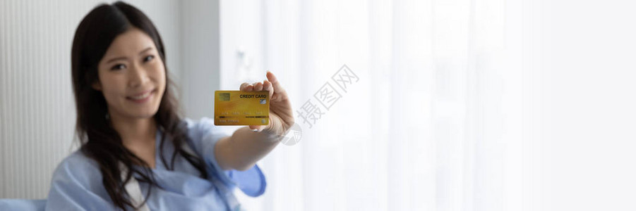 医院病人床上快乐的亚洲女孩微笑并出示信用卡概念支付医疗全景网页横幅图片