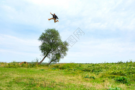 一个人在夏日跳过一棵生长在田野上的树穿着橙色袜子的不可思图片
