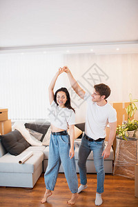 一对年轻夫妇在纸箱附近的客厅里跳舞娱乐图片