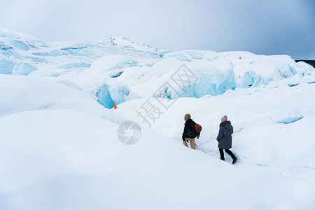 两名徒步旅行者在阿拉斯加马塔努斯卡冰川的雪地上徒步他们正沿着一条小路进入冰洞寒假期间的极端冒险在图片