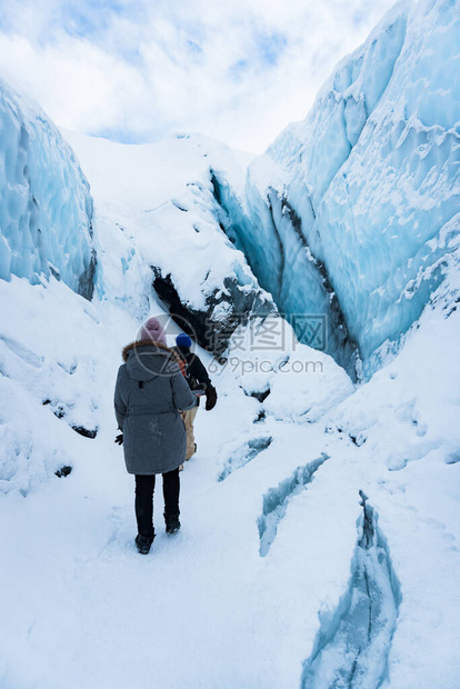 两名徒步旅行者在阿拉斯加马塔努斯卡冰川的雪地上徒步他们正沿着一条小路进入冰洞寒假期间的极端冒险在图片