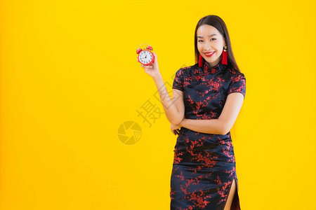 肖像美丽的亚洲年轻女穿着中式服装秀钟或黄色孤图片