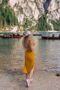一件衣服和划船的女孩在一个山湖的岸边有木船的白图片