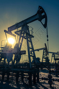 油泵钻机石油和天然气生产油田现场泵千斤顶正在运行用于化石燃料输出和原油生产的钻井平台全球冠状COVID19危机背景图片