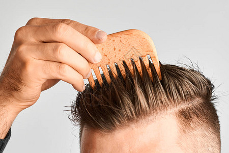 年轻人用木梳造型他的头发在家做头发造型健康头发和去屑洗发图片