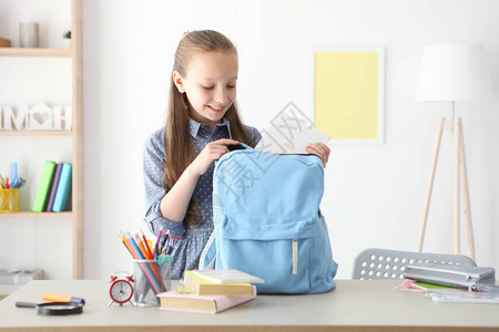 可爱开朗的女学生把文具放在背包里为上学做准备回到学校背景图片