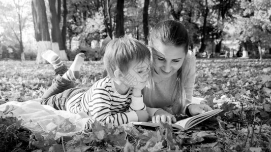 家庭阅读故事书的黑色和白色肖像同时躺在图片