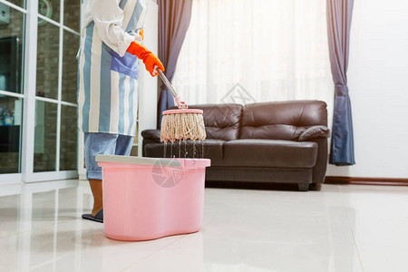 身戴保护手套的亚洲年轻美女使用平滑的湿毛抹布在屋子里打扫地板时图片