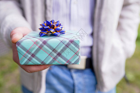 男人手里拿着蝴蝶结的绿色礼盒图片