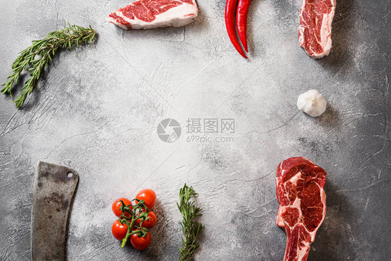 生混合牛肉黑安格斯战斧牛排或斯宾塞牛排与夹头卷用肉美国切肉刀在灰色石桌板上切割顶部视图框架与调味料西红柿大蒜迷迭香图片