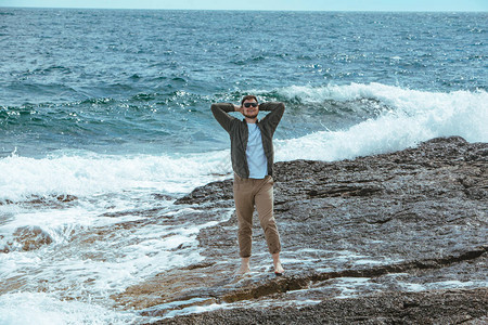 男子在寒风的暑假中走在岩石海滩图片