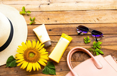 防晒霜spf50化妆品保健用润肤露粉色手提包太阳镜生活方式女人的帽子和生活方式女人的黄色花向日葵在夏天背景图片