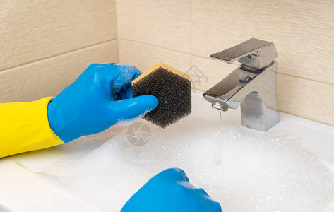 打扫浴室手拿着橡胶手套用洗涤剂清洗脸盆良好和高质量工作的概图片