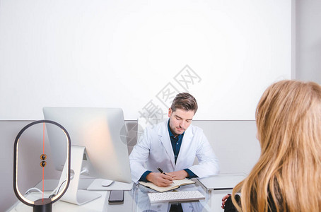 年轻医生在现代办公室为一位病人看诊图片