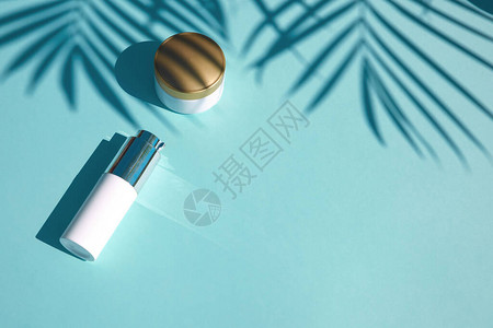 在柔和的蓝色背景与热带棕榈叶的化妆品天然产品铭文的笔记本平躺具有SPF防晒功能图片
