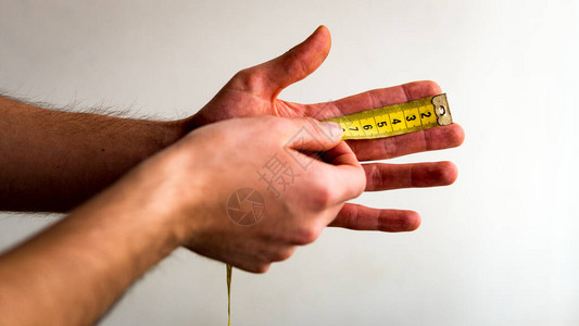 用黄色卷尺测量左手食指的人白色背景图片