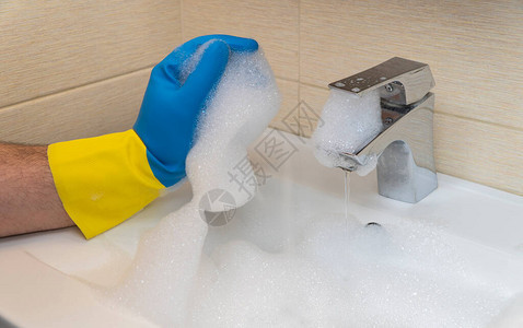 打扫浴室手拿着橡胶手套用洗涤剂清洗脸盆良好和高质量工作的概图片