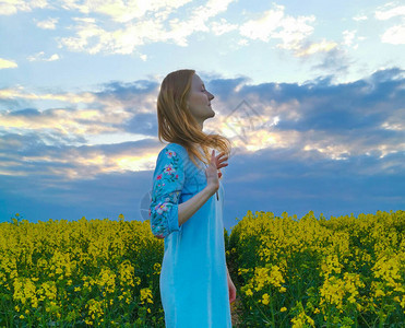 暴风雨前油菜花田里的金发美女图片