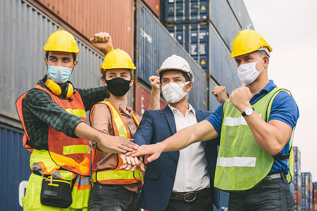 建筑工人团队正在与仓库港身穿蓝色西装的商人合作开展工作他们都戴着口罩戴着口图片