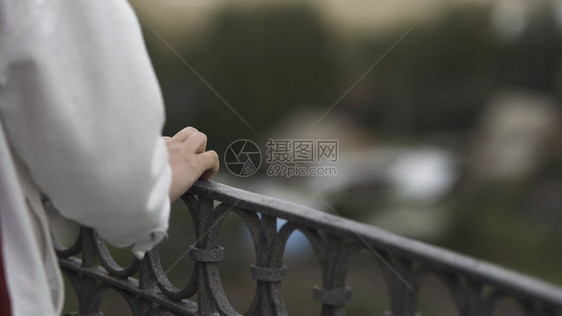 阳台上一名身穿白色衣服的妇女的后视图在模糊的背景下关闭阳台的女触摸图片