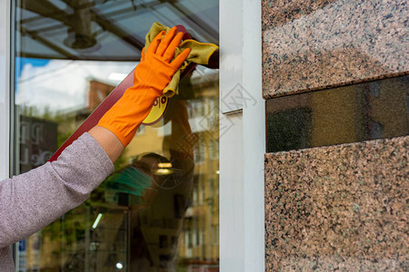 清洁剂在用于消毒的冠状流行期间擦除商店前门和图片