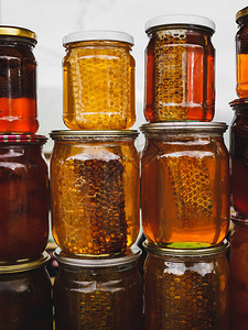 五颜六色的蜂蜜和蜂蜜梳子和不同的蜜饯在当地市场的罐子里关闭亚美图片
