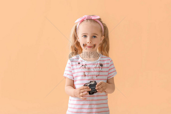穿脏衣服的小女孩在颜色背景上吃巧克力蛋糕图片