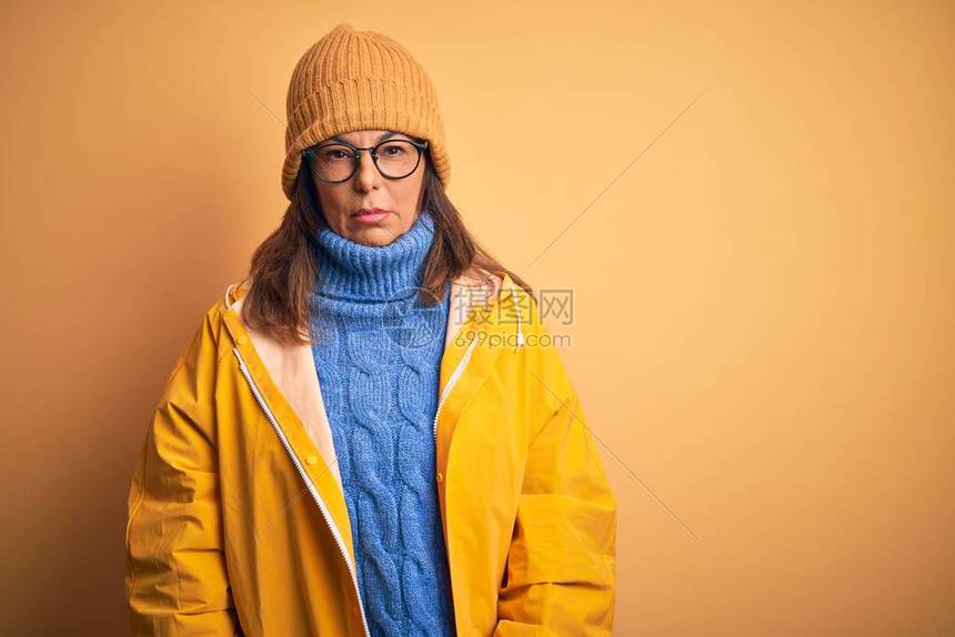 身穿黄雨衣和冬帽的中年妇女因孤立的背景而感到沮丧图片